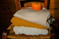 stack of warm knitted sweaters in sunlight on wooden chairs across wooden dresser close-up and orange persimmon on the top. Warm Royalty Free Stock Photo