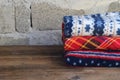 Stack of warm woolen blankets on wooden background. Home cosiness. Colorful plaids