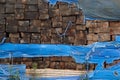 Stack of weathered wooden railroad cross ties covered by blue torn plastic Royalty Free Stock Photo