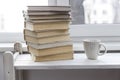 A stack of white-bound books is on table against the background of the window. The cup of tea is next to books. School Royalty Free Stock Photo