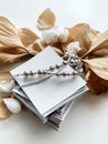 Stack of white cards with silver beaded necklace and dried flowers on a white surface close up view Royalty Free Stock Photo