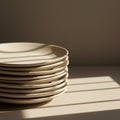 A stack of white ceramic plates sits in soft, diffused sunlight, casting gentle shadows Royalty Free Stock Photo