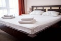 Stack of white clean bath towels on bed in modern hotel bedroom interior, copy space. Royalty Free Stock Photo