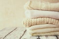 Stack of white cozy knitted sweaters on a wooden table