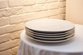 A stack of white dinner plates on a table against a brick wall background Royalty Free Stock Photo