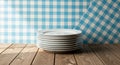 Stack of White Dinner Plates on a Wooden Table with Blue Gingham Background dinnerware clean Royalty Free Stock Photo
