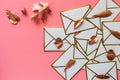 Stack of white envelopes with golden leaves on blush pink background with copy space