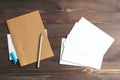 Stack of white envelopes on a wooden background. A blue handle and a sheet of kraft paper. Flat lay, top view Royalty Free Stock Photo