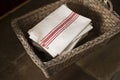 Stack of White Napkins with Red Stripes in Woven Basket