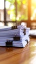 Stack of white paper documents held together by black binder clips on wooden table Royalty Free Stock Photo