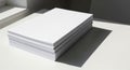 A stack of white paper sheets is neatly arranged on a flat surface, casting a distinct shadow to Royalty Free Stock Photo