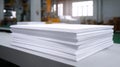 Stack of white paper sheets on table in printing facility with industrial equipment in background Royalty Free Stock Photo