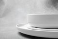 Stack of white porcelain plates and bowls on neutral gray background. copy space Royalty Free Stock Photo