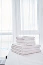 Stack of white terry bath towels on bed sheet in modern hotel bedroom interior, copy space Royalty Free Stock Photo