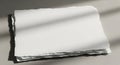 A stack of white, torn-edged paper rests on a smooth surface, with shadows casting Royalty Free Stock Photo