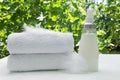 Stack of white towels, glass bottle of softener and feathers as a symbol of delicate washing Royalty Free Stock Photo