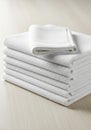 Stack of white towels on a smooth, light wooden surface. The towels are neatly folded and arranged Royalty Free Stock Photo
