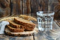 Stack of Whole Grain Bread with Seeds on Rustic Wooden Table beside a Clear Glass of Water Royalty Free Stock Photo