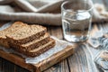 Stack of Whole Grain Bread with Seeds on Rustic Wooden Table beside a Clear Glass of Water Royalty Free Stock Photo