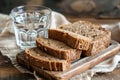 Stack of Whole Grain Bread with Seeds on Rustic Wooden Table beside a Clear Glass of Water Royalty Free Stock Photo