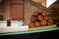 Stack of wood logs and watering cans with flowers on a narrow boat on a London canal. Royalty Free Stock Photo