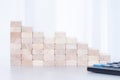 Stack of wooden blocks, calculator on whete sunlight background. Step down, fall, recession, crisis concept Royalty Free Stock Photo