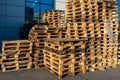 A stack of wooden pallets in an internal warehouse. An outdoor pallet storage area under the roof next to the store. Piles of Euro