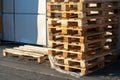 A stack of wooden pallets in an internal warehouse. An outdoor pallet storage area under the roof next to the store. Piles of Euro