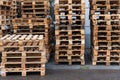 A stack of wooden pallets in an internal warehouse. An outdoor pallet storage area under the roof next to the store. Piles of Euro
