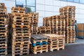 A stack of wooden pallets in an internal warehouse. An outdoor pallet storage area under the roof next to the store. Piles of Euro