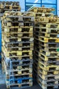 A stack of wooden pallets in an internal warehouse. An outdoor pallet storage area under the roof next to the store. Piles of Euro