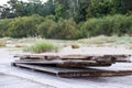 A stack of wooden planks placed on the edge of the sea against a Greenwood background Royalty Free Stock Photo