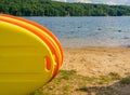 Stack of yellow and orange paddleboards on sandy beach by a lake Royalty Free Stock Photo