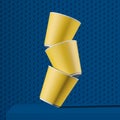 Stack of yellow paper cups falling on blue table Royalty Free Stock Photo