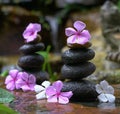 Stack of zen stones with flowers next to a garden mini waterfall Royalty Free Stock Photo