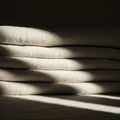 Stacked beige fabric with a textured surface is illuminated by soft, dappled light, Royalty Free Stock Photo