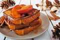 Stacked caramel apple cinnamon french toasts. Table scene on a white wood background.