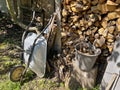 Stacked chopped firewood in rustic woodpile in the yard with metal wheelbarrow and plastic bucket with wooden logs. Royalty Free Stock Photo