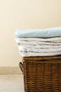 Stacked clean folded cotton bedlinen on wicker chest white wall background. Laundry cleanliness concept. Provence Mediterranean