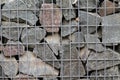 Stacked cobblestones, fixed with steel mesh. Wall of stones under grid