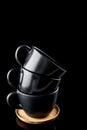 Stacked Coffee Cups, Three Dark Modern Cups stacked on a wooden tray, short from nice angle isolated on black Royalty Free Stock Photo