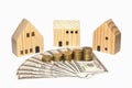 Stacked coin on US dollar bills and three wooden house, isolated on white background Royalty Free Stock Photo