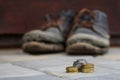 Stacked coins on blurred background of a pair of dirty old boots. The concept of poverty  homelessness  lack of money. Gray Royalty Free Stock Photo
