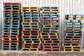 Stacked of colorful rough wooden pallets background at cargo, warehouse.