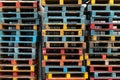 Stacked of colorful rough wooden pallets background at cargo, warehouse.