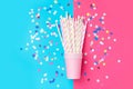 Stacked drinking paper cup striped straws colorful confetti scattered on bright duotone fuchsia blue background. Birthday Royalty Free Stock Photo