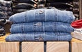 Stacked of folded jeans at store on wooden shelf