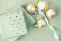 Stacked gift boxes wrapped in grey silver paper with polka dots pattern. Wooden spool with white silk ribbon, Christmas balls.