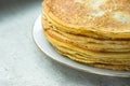 Stacked golden crepes on white plate on linen cloth background, closeup, breakfast