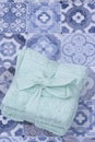 Stacked green face towels flannels tied with ribbon and a bow. On a blue tiled surface